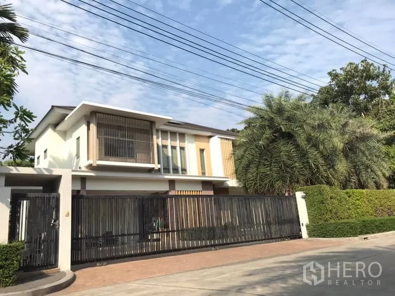 Detached House for sale in Saphan Sung, Bangkok - Front exterior of modern two-storey detached house with sliding metal gate and mature palm.