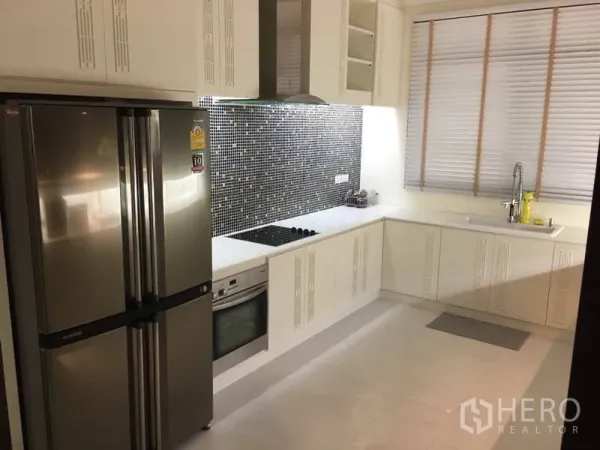 Detached House for rent in Bang Phli, Samut Prakan - Modern white kitchen with mosaic backsplash, built-in oven, cooktop, hood, and a stainless French-door refrigerator.
