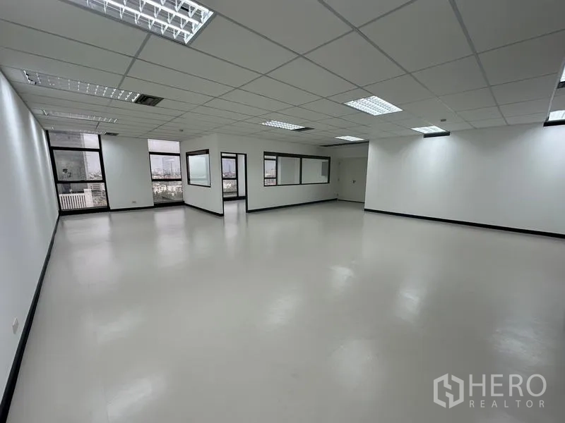 Office Space for rent - Bright open office floor showing city views through windows and grid ceiling lighting.