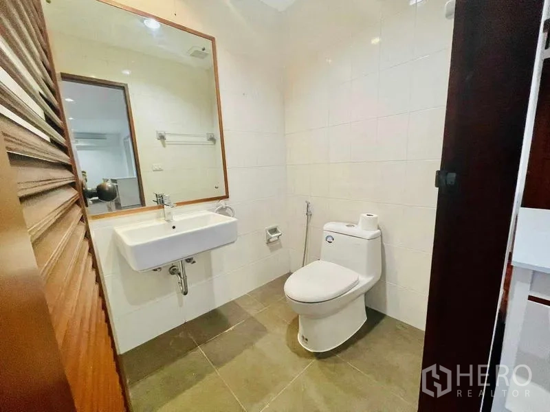 Condominium for rent - Bright guest bathroom with wall mirror, sink, and toilet.