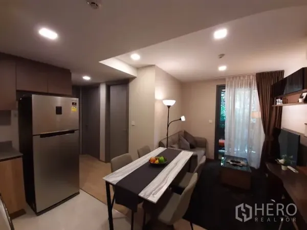 公寓 出租或出售在Watthana, Bangkok - 小厨房与不锈钢双门冰箱，毗邻餐区与客厅并通向阳台。