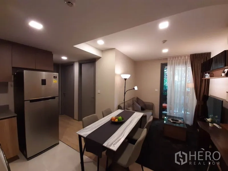 公寓 出租或出售在Watthana, Bangkok - 小厨房与不锈钢双门冰箱，毗邻餐区与客厅并通向阳台。
