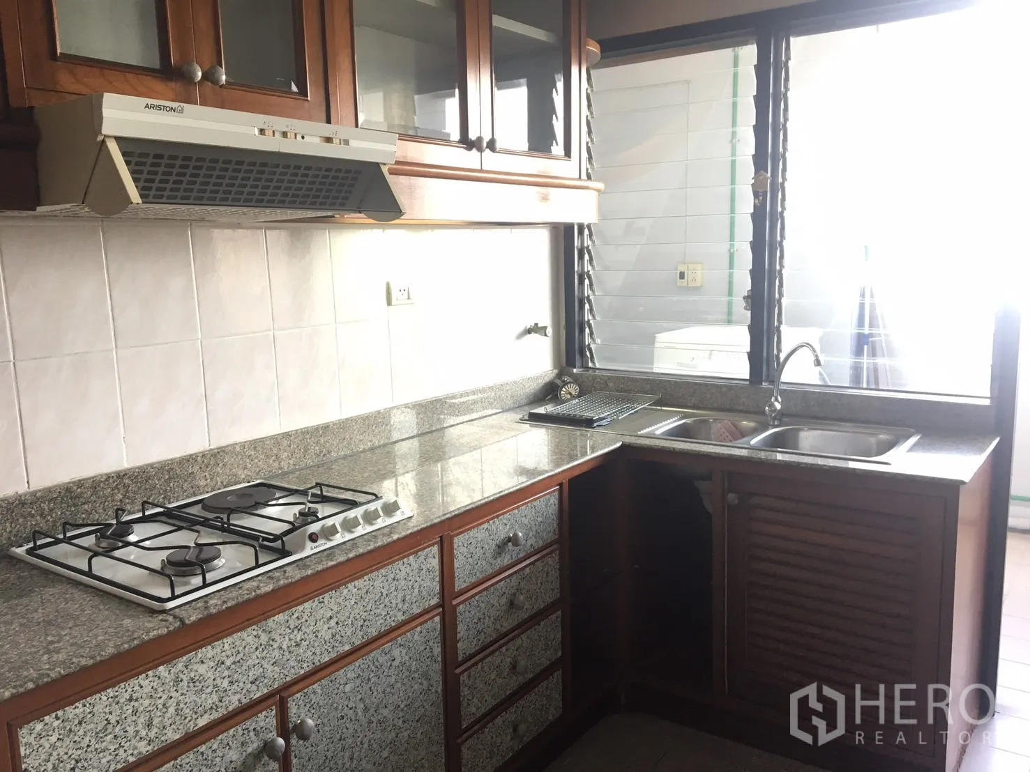 公寓 出租在Watthana, Bangkok - U 型厨房，花岗岩台面、燃气灶、抽油烟机、双槽水槽与采光窗。