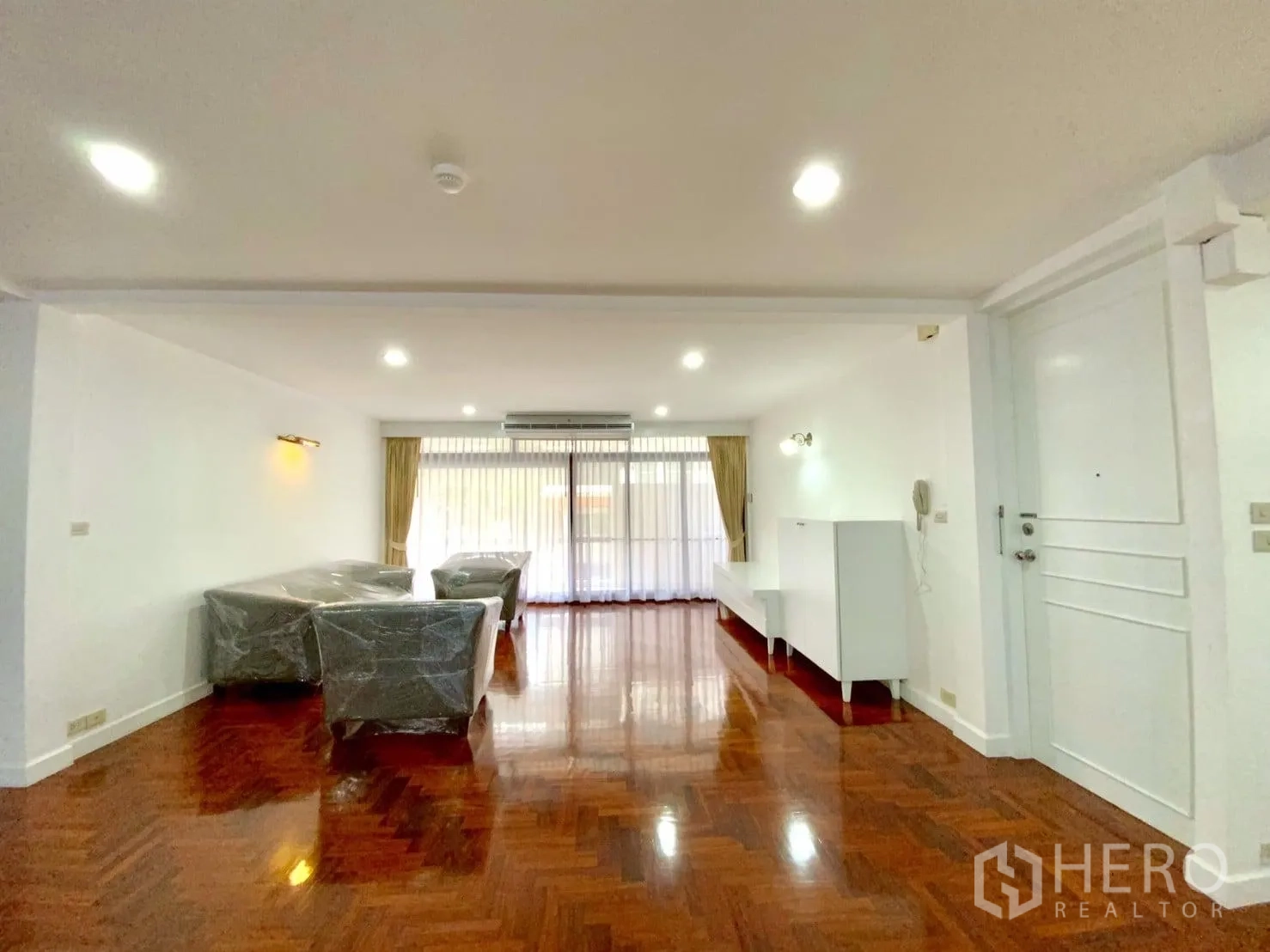 公寓 出租在Watthana, Bangkok - 客厅朝向宽大阳台门，灯光充足，沙发包裹保护膜。