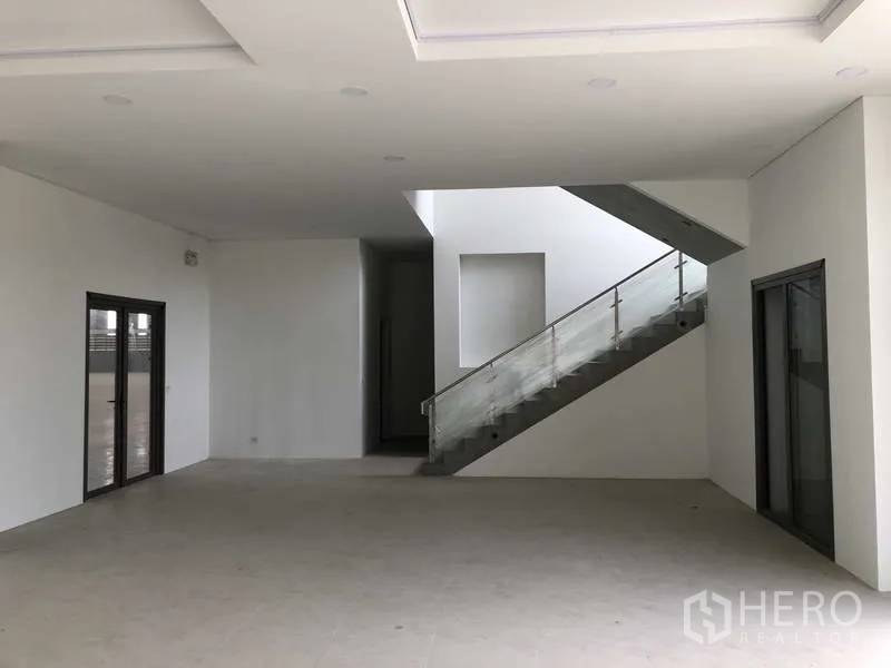 Factory for rent or sale in Samut Prakan - Office lobby with stairway, glass doors, and bright white walls.