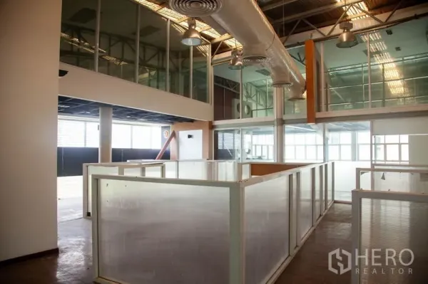 Warehouse for rent in Prawet, Bangkok - Industrial interior showing mezzanine glass offices, suspended HVAC ducts and translucent partitions within a Bangkok warehouse.