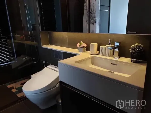 公寓 出租在Huai Khwang, Bangkok - 现代浴室，简洁洗手台、坐便器与玻璃淋浴间。