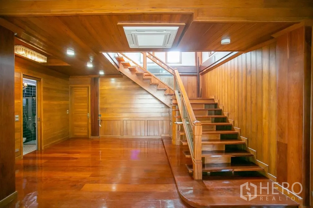 独栋房屋 for rent or sale in Huai Khwang, Bangkok - 宽敞木质客厅大厅，带楼梯、筒灯与卫生间入口。
