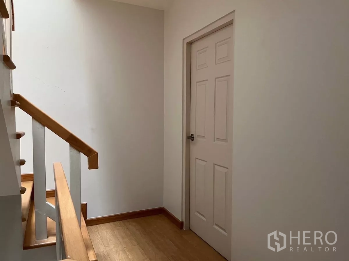 Townhouse for rent in Bang Kho Laem, Bangkok - Stair landing with wood handrails and a bedroom door.
