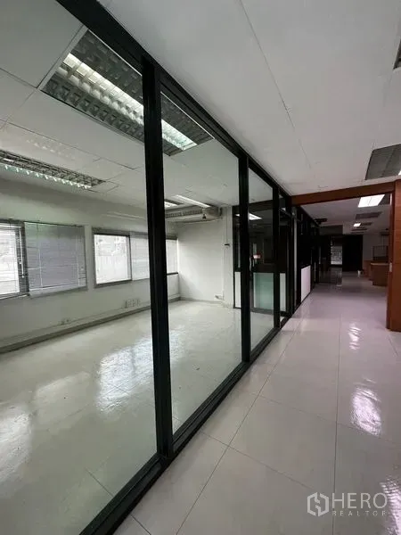 Office Space for rent in Pathum Wan, Bangkok - Hallway lined with floor-to-ceiling glass offices and tiled floor.