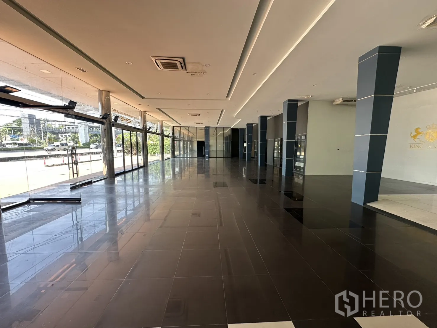 Showroom for rent in Suan Luang, Bangkok - Bright showroom aisle with blue columns and recessed ceiling lights.
