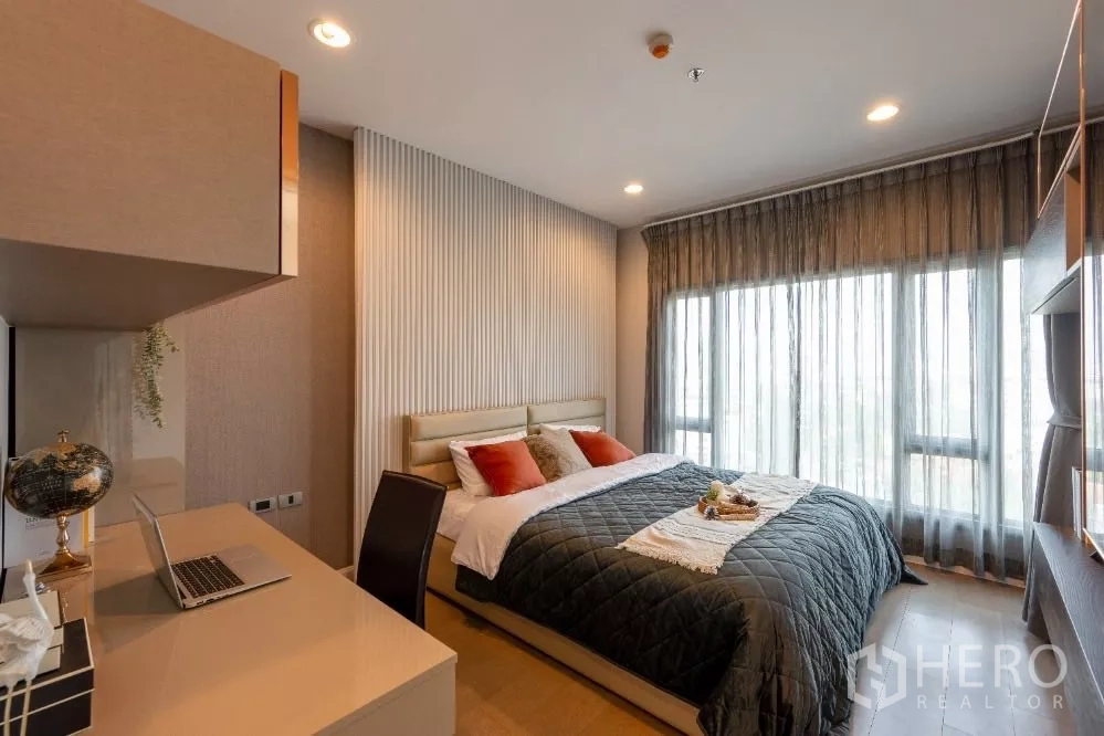 Condominium for rent or sale in Khlong Toei, Bangkok - Bright master bedroom featuring a work desk and floor-to-ceiling sheer curtains.