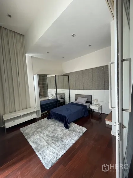 Townhouse for rent or sale in Chatuchak, Bangkok - Cozy guest bedroom featuring mirrored wardrobe doors and a plush rug.