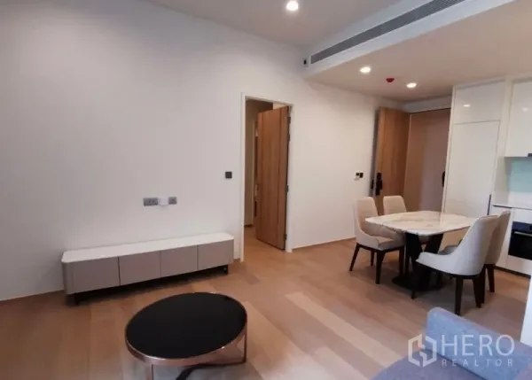 Condominium for rent in Bang Rak, Bangkok - Living and dining space with round coffee table, low TV console and light wood floors.