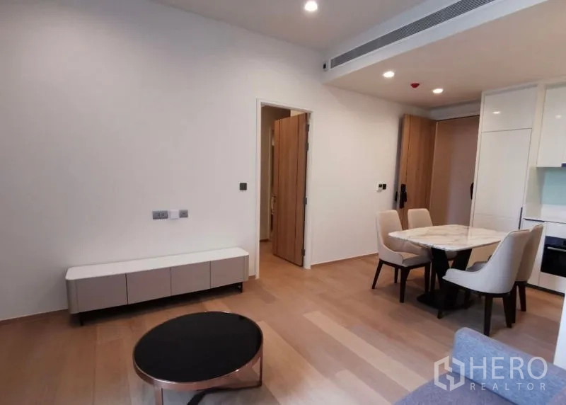 Condominium for rent in Bang Rak, Bangkok - Living and dining space with round coffee table, low TV console and light wood floors.