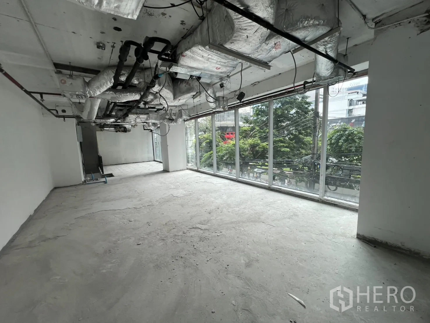 零售空间 出租在Bang Rak, Bangkok - 明亮的上层，宽大窗墙俯瞰绿树与车道。