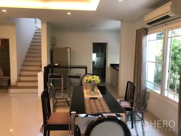 Detached House for rent or sale in Bang Kapi, Bangkok - Open dining zone by the staircase with breakfast counter, air conditioning and garden-view windows.