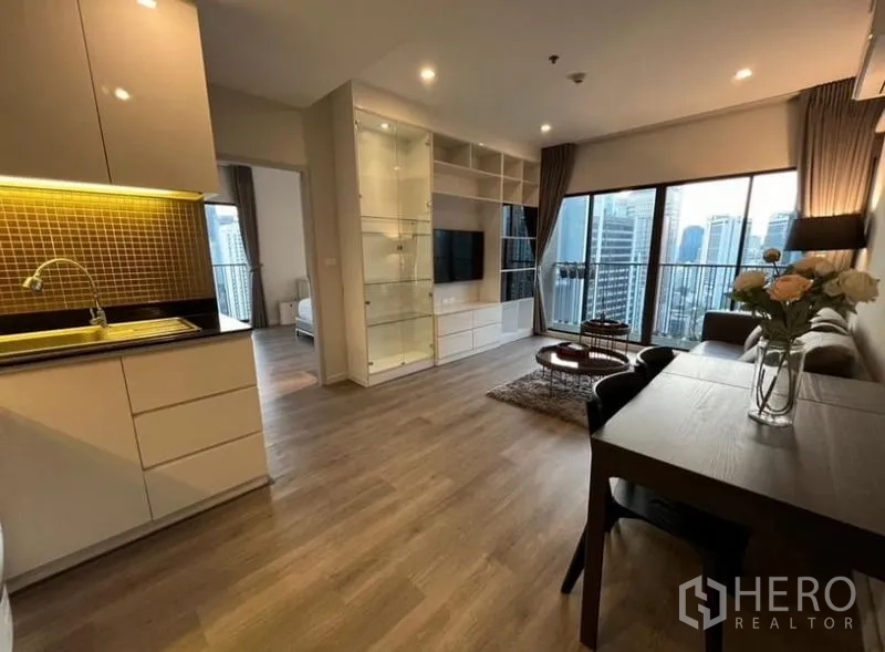 Condominium for rent in Bangkok - Dining, kitchen and lounge in a modern open layout with wood floors and large balcony glazing.