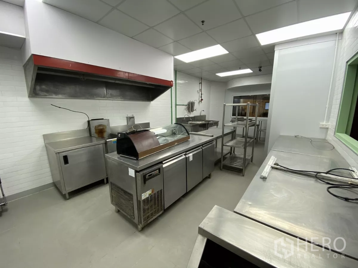 Retail Space for rent - Kitchen view showing refrigeration, range hood and mobile shelving racks.