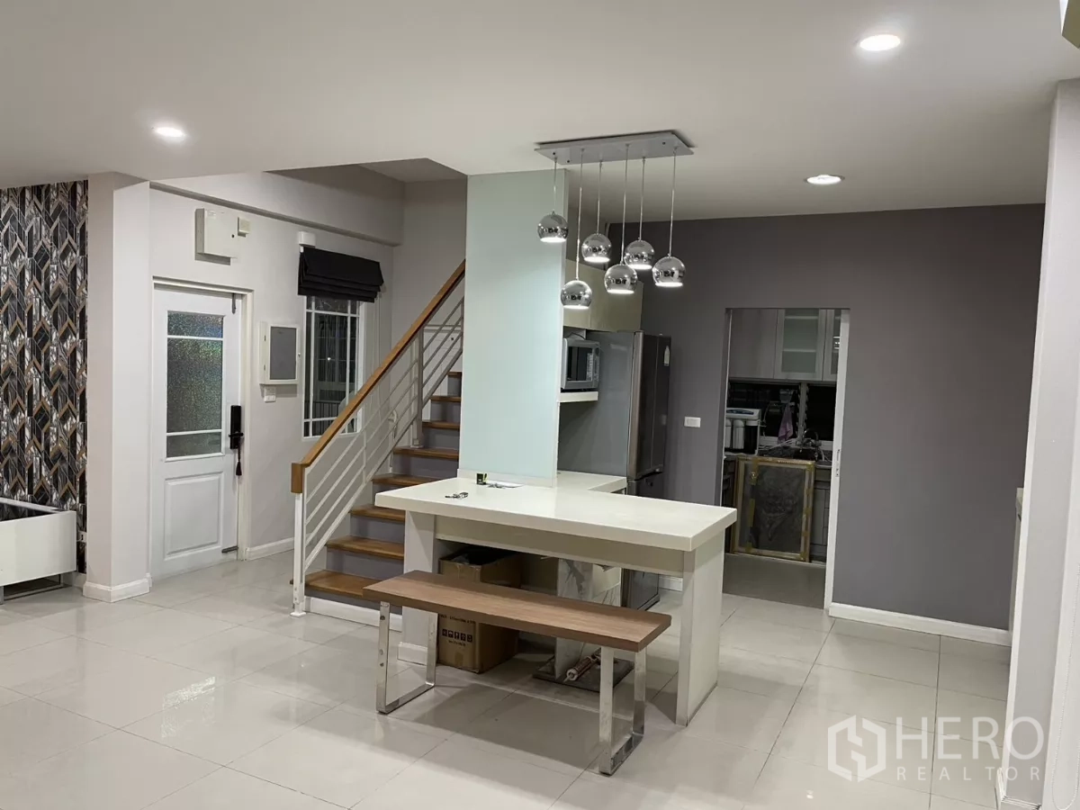 Detached House for rent in Bang Kapi, Bangkok - Bright kitchen zone with island, pendant lights and wooden stairway adjacent.