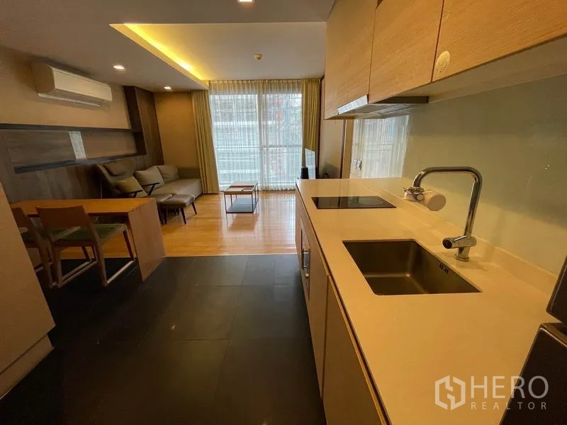 公寓 出售在Watthana, Bangkok - 走廊式厨房，石质台面、洗槽与炉灶，朝向客厅。