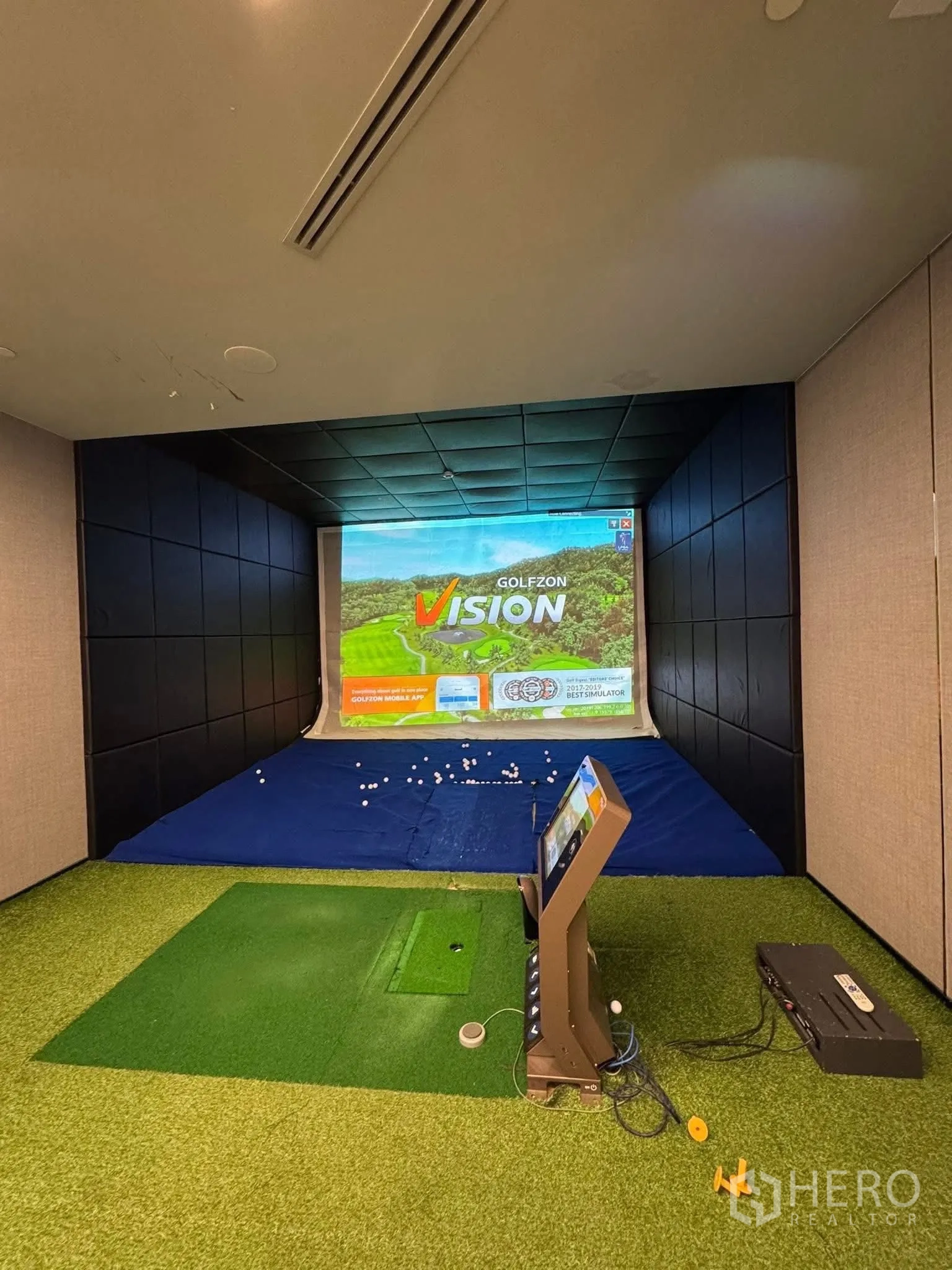 Condominium for rent in Khlong Toei, Bangkok - Indoor golf simulator room with screen, hitting mat and scattered balls.