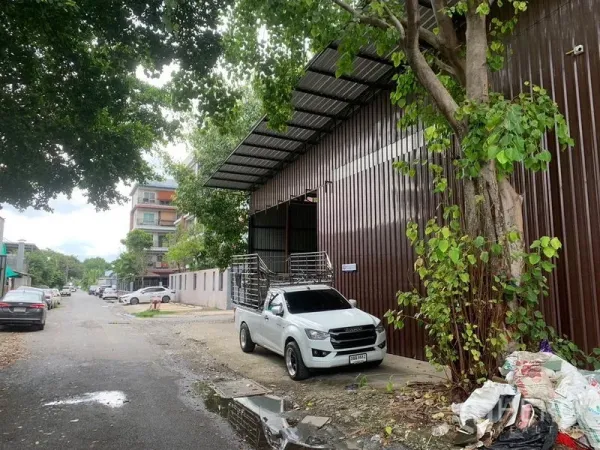 货栈 出租在Bang Kapi, Bangkok - 棕色金属仓库街景，带有遮雨装卸区与路边停车位。