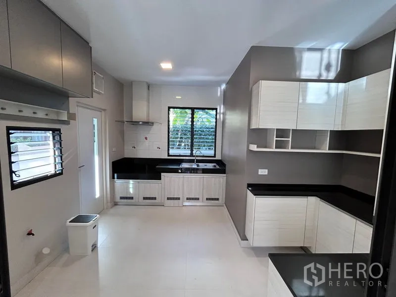 บ้าน ให้เช่าหรือขายในPrawet, Bangkok - ห้องครัวกว้าง เคาน์เตอร์สีดำ ตู้ขาว และหน้าต่าง