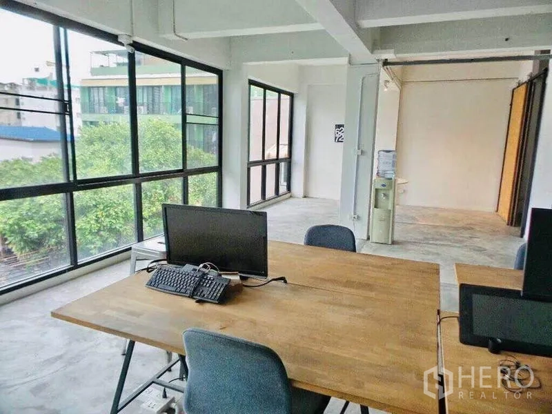 Home Office for rent or sale in Din Daeng, Bangkok - Corner office with wraparound windows, wooden desk and city and tree views.
