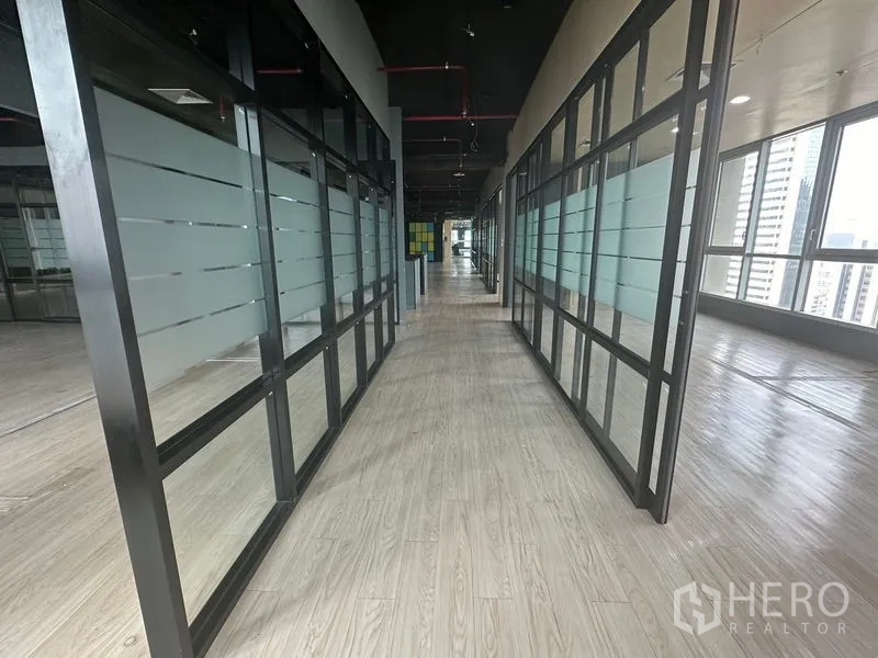Office Space for rent in Bang Rak, Bangkok - Long corridor lined with glass partitions on both sides and wood-look flooring.