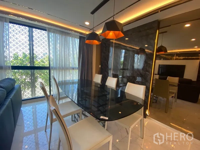 Townhouse for sale in Yan Nawa, Bangkok - Dining area with black glass table, modern pendant lights and window views beside a mirrored wall.