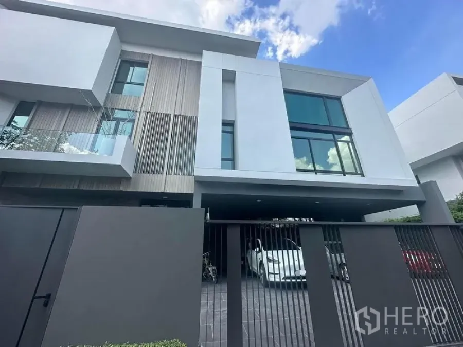 Detached House for sale in Saphan Sung, Bangkok - Modern three-storey detached house facade with full-height windows, gated driveway and carport in Bangkok.