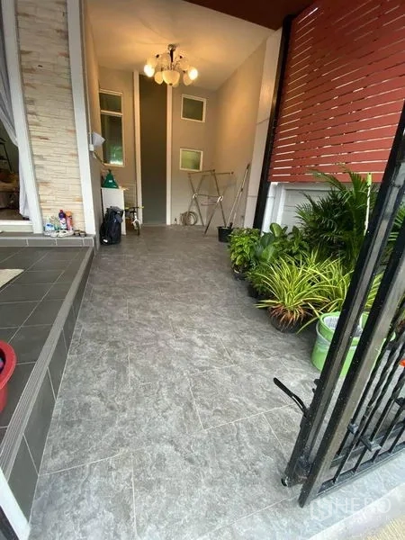 Townhouse for sale in Saphan Sung, Bangkok - Front entry terrace with tiled floor, hanging lights and red privacy screen with potted plants.