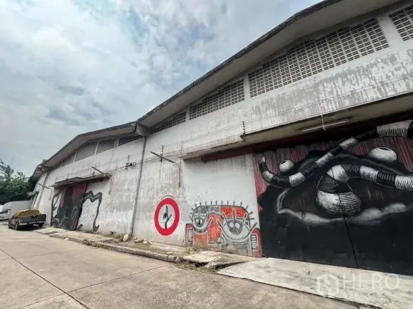Warehouse for rent in Khlong Toei, Bangkok - Warehouse exterior with wide roller doors, loading bays, and street‑front facade featuring mural art.