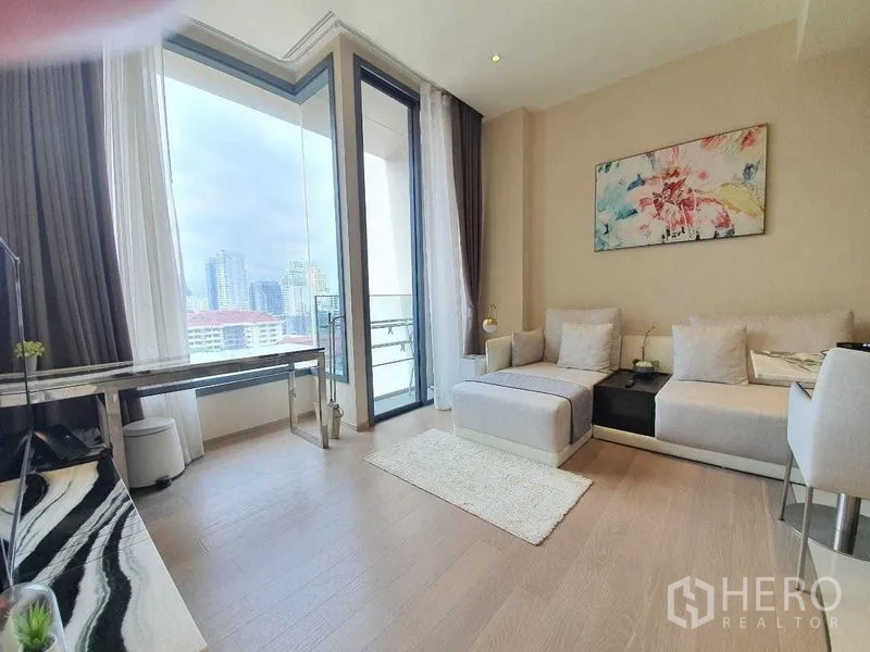 公寓 出租或出售在Watthana, Bangkok - 舒适客厅，转角沙发与墙面装饰画，通向观景阳台的全高玻璃。