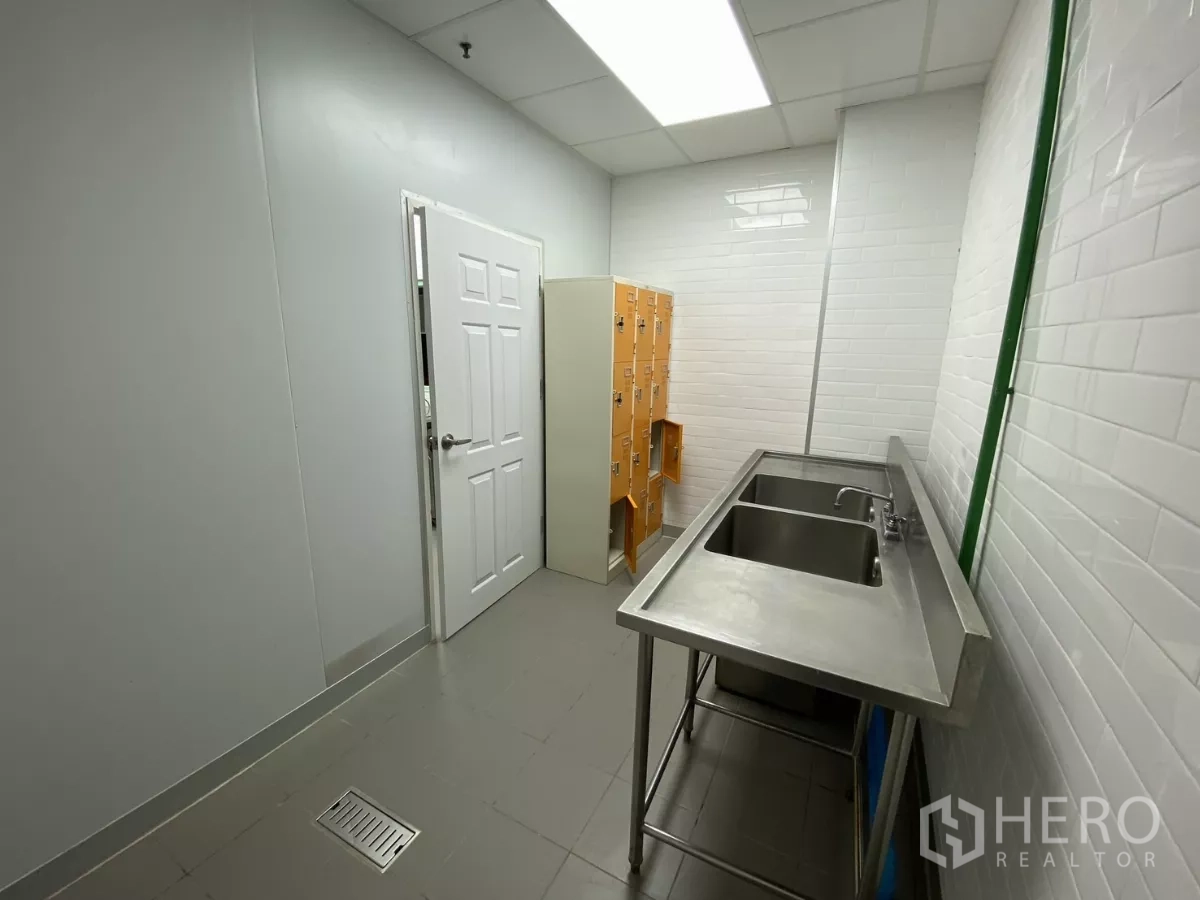 Retail Space for rent - Staff room with lockers and a stainless sink under bright lighting.