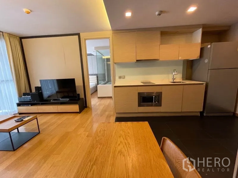 公寓 出售在Watthana, Bangkok - 浅木色厨房，设灶台、微波炉，通向卧室的门。