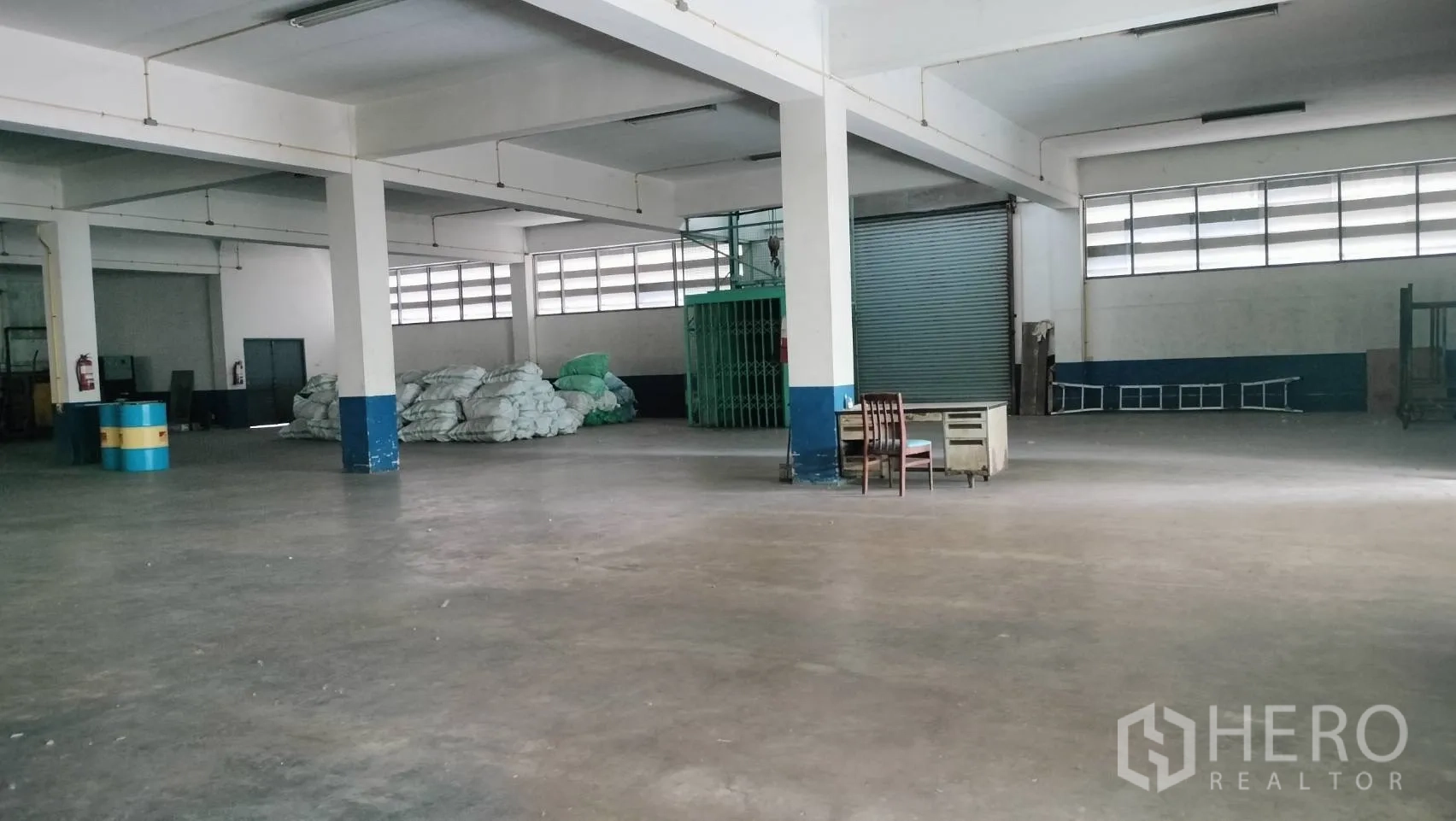 โรงงาน for rent in Lat Krabang, Bangkok - ฮอลล์การผลิตกว้าง พื้นคอนกรีต เสาโครงสร้าง และประตูม้วน พร้อมโต๊ะทำงานเล็ก.
