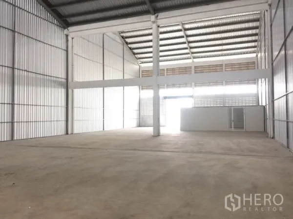 Factory for rent in Mueang Samut Prakan, Samut Prakan - Spacious factory floor with tall columns, ventilated siding and a large entry opening.