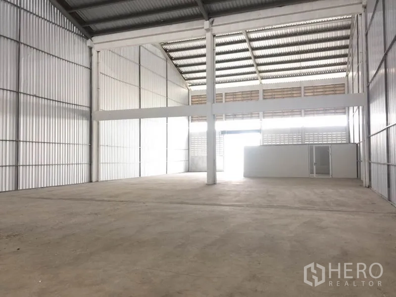 Factory for rent in Mueang Samut Prakan, Samut Prakan - Spacious factory floor with tall columns, ventilated siding and a large entry opening.
