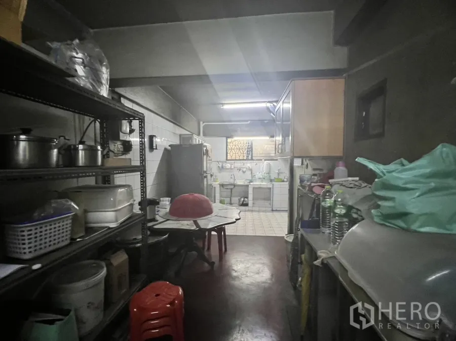 Retail Space for rent in Watthana, Bangkok - Back-of-house prep area with metal shelving, fridge and a tiled sink under fluorescent lighting.