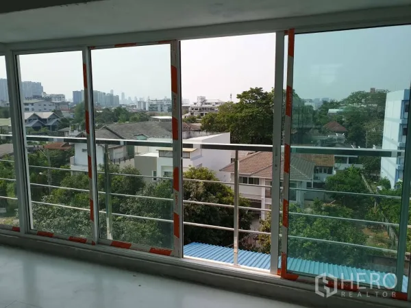 办公空间 出租或出售 - 通过推拉落地门看到社区与城市天际线，带阳台栏杆。