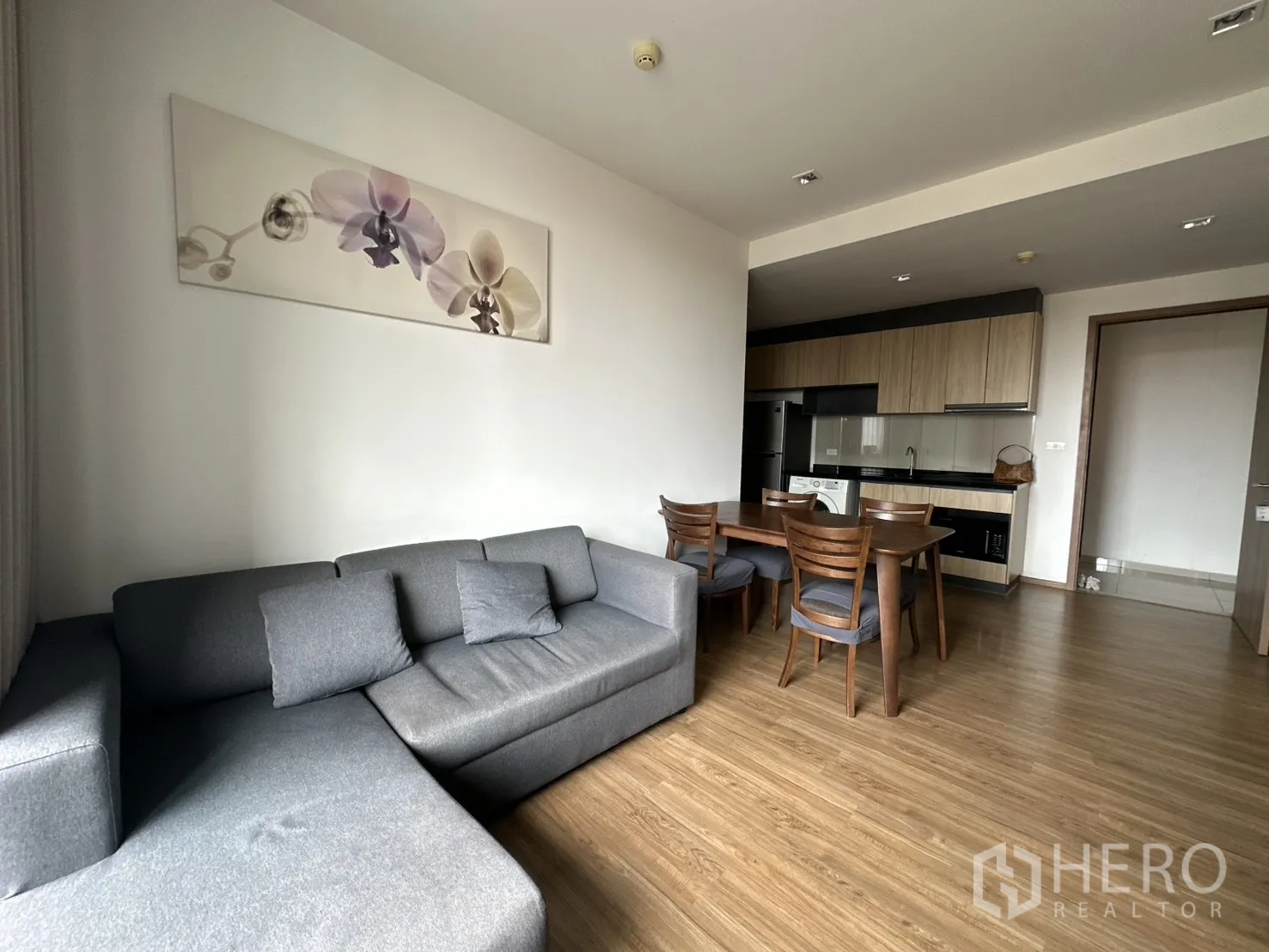 公寓 for rent in Watthana, Bangkok - 开放式客餐厅，L 型沙发与四人餐桌。