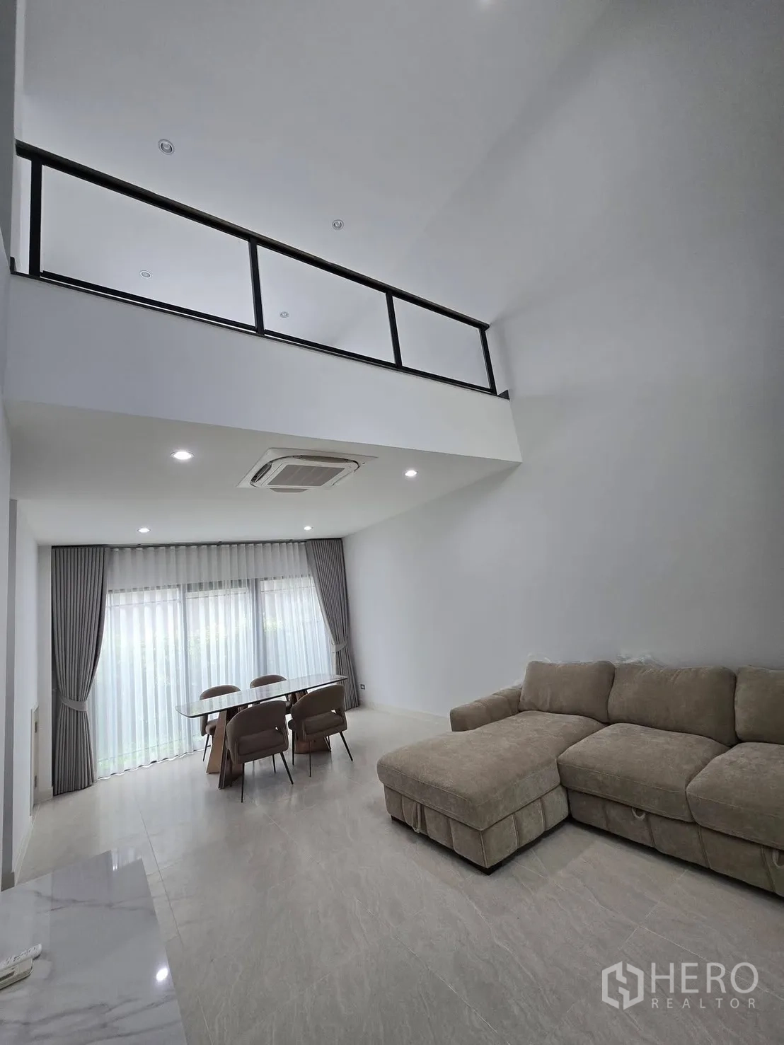 บ้านแฝด for rent in Suan Luang, Bangkok - ห้องนั่งเล่นเพดานสูงพร้อมชั้นลอยด้านบนและโซฟาตัวแอลด้านล่าง.