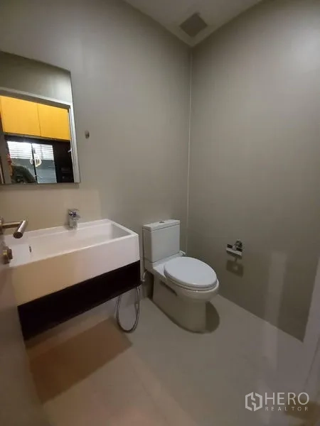 Townhouse for rent in Suan Luang, Bangkok - Guest powder room with wall-hung vanity, mirror and toilet.