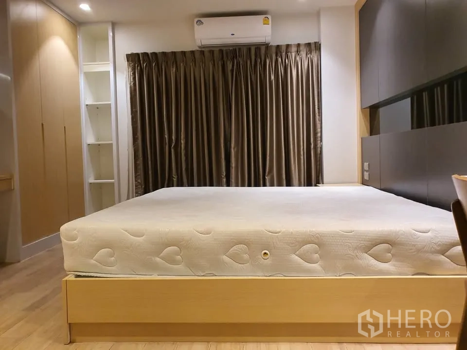 Condominium for rent in Watthana, Bangkok - Bedroom with king-size bed, floor-to-ceiling curtains, built-in closets and air conditioner.