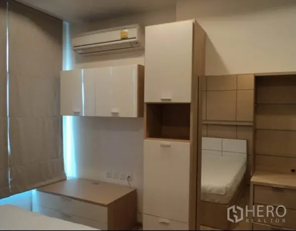 Condominium for rent in Khlong Toei, Bangkok - Bedroom with built-in storage, air conditioner, window blinds, and a bed.