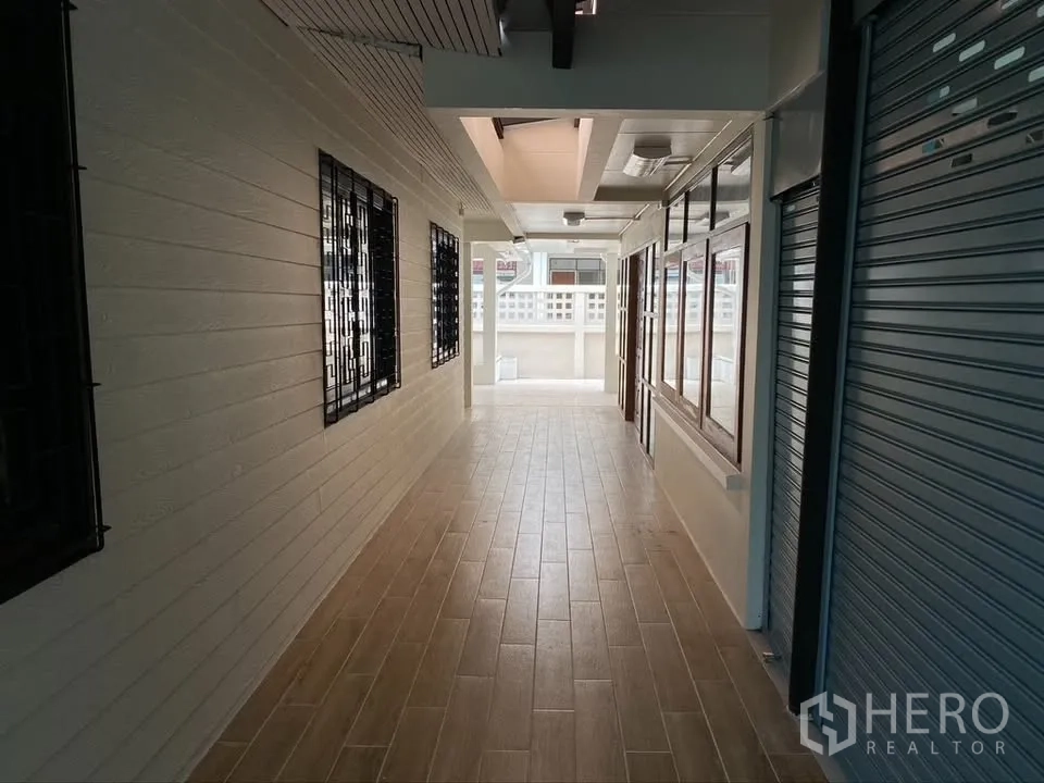Detached House for rent in Suan Luang, Bangkok - Covered corridor with wood-look tiles, metal shutters, and window grilles.