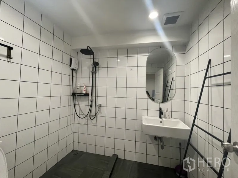 Home Office for rent or sale in Watthana, Bangkok - Bathroom with white wall tiles, rain shower, vanity and arched mirror.