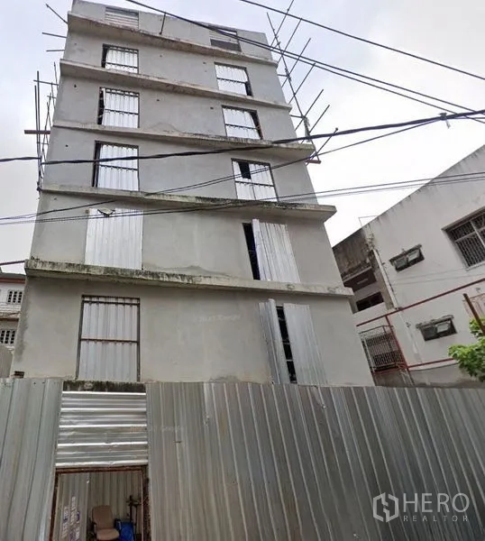 带办公室的家 出租 - 多层混凝土Home Office外立面，前方为金属围挡，街景视角。